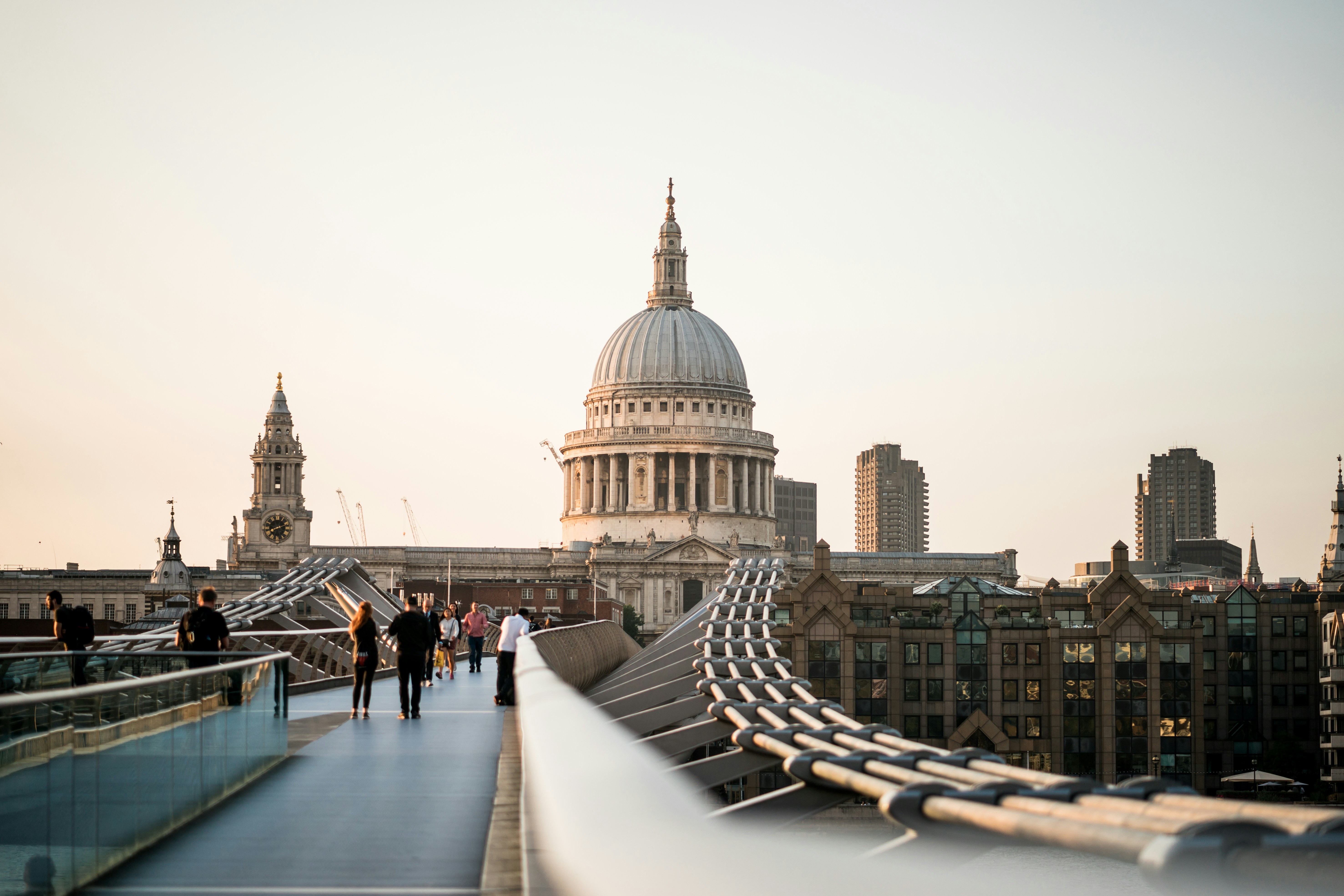 Visitors walking along the Millennium Bridge towards St Paul's Cathedral at dusk, London